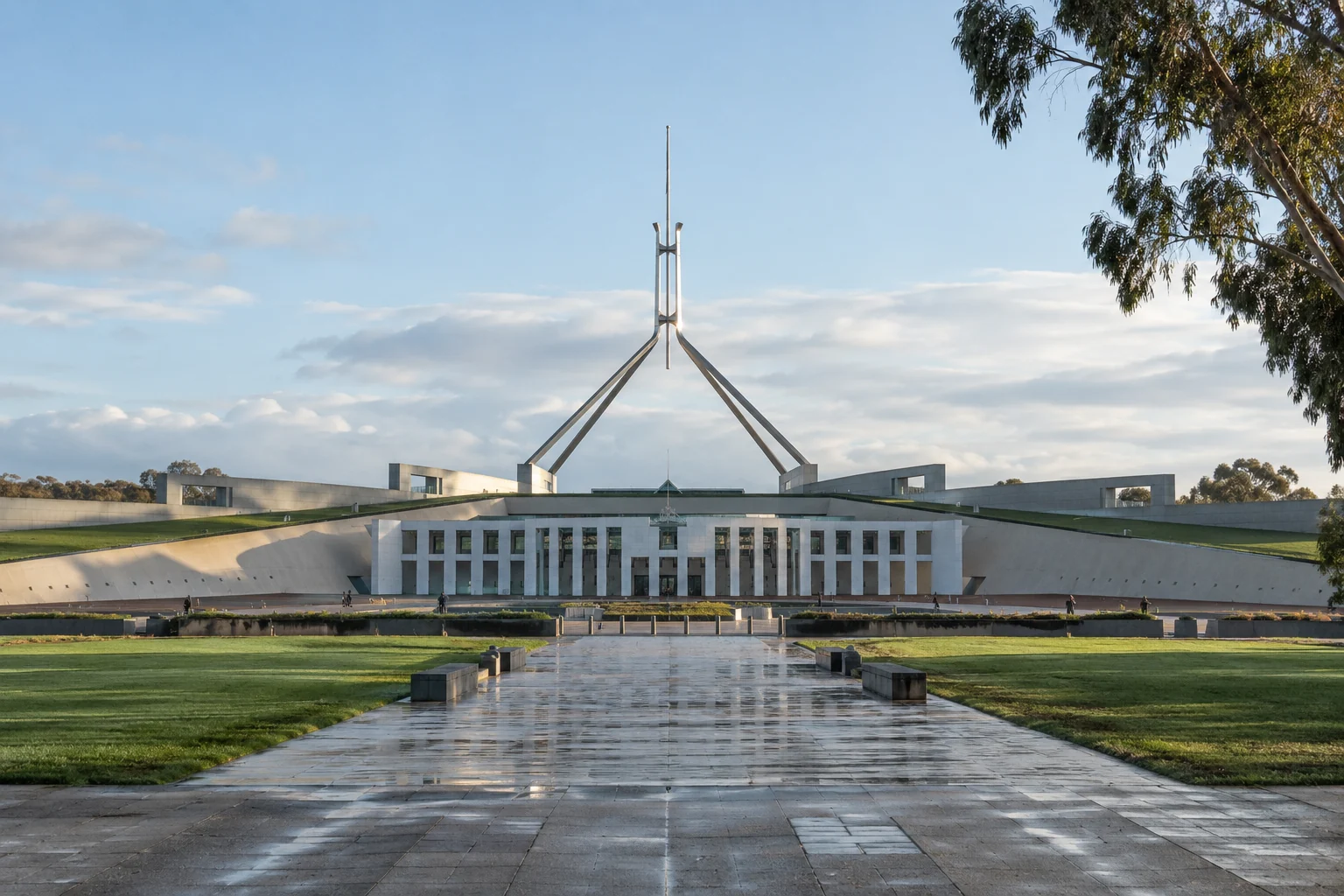 Australian Parliament House in Canberra beyond lawns and a rain-washed stone approach.